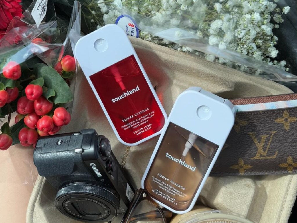 touchland fragrance mists next to camera, flowers and wallet