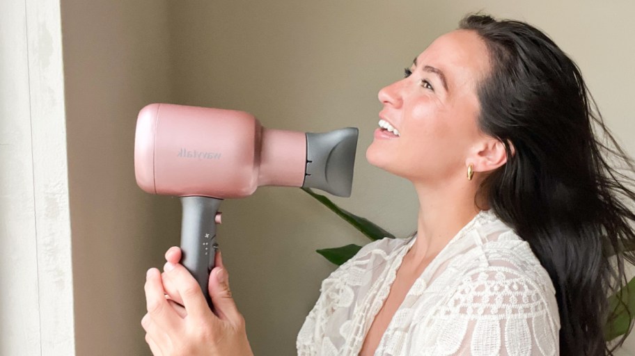 woman holding a pink hair dryer