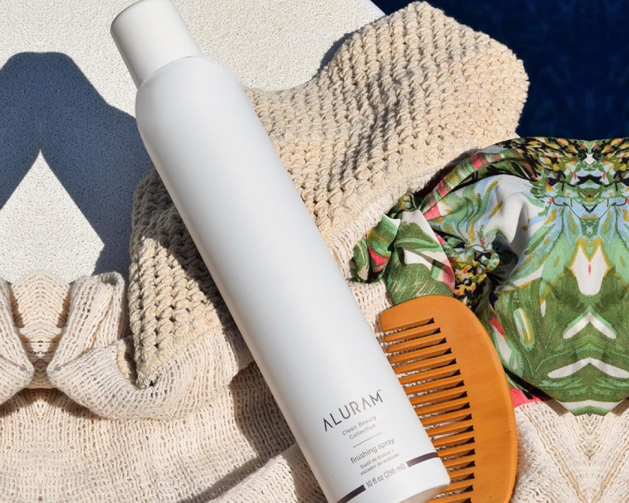aluram hairspray on beach towel next to comb