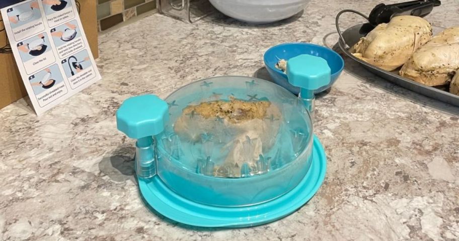 chicken shredder on counter with chicken breasts on pan next to it