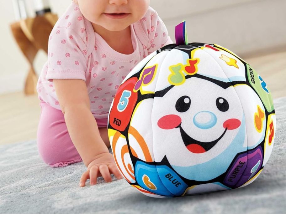 baby crawling towards Fisher-Price Laugh & Learn Singin' Soccer Ball on floor