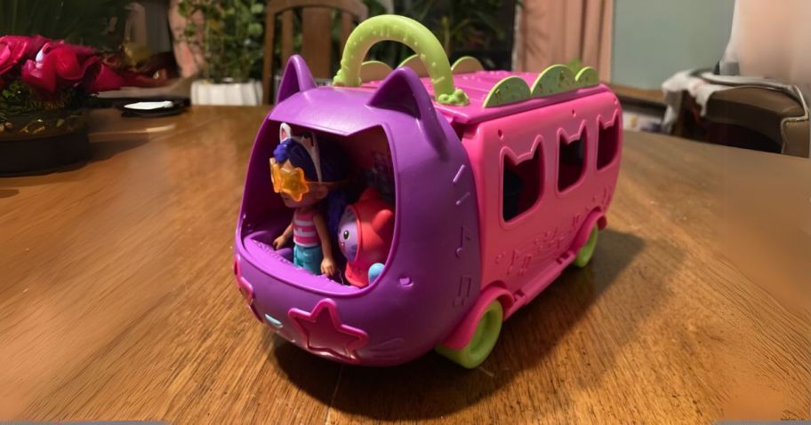 pink and purple Gabby's Dollhouse Celebration Party Bus on table