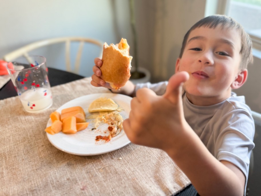 boy giving thumbs up eating meatball sub