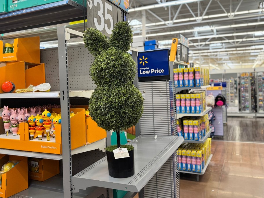 a tall green bunny rabbit shaped faux topiary in a black pot in Walmart cart in the middle of the Easter decor aisle
