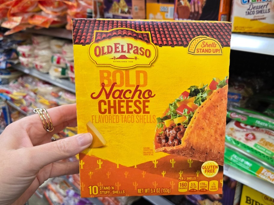 hand holding a box with Old El Paso Stand 'N Stuff Bold Nacho Cheese Flavored Taco Shells