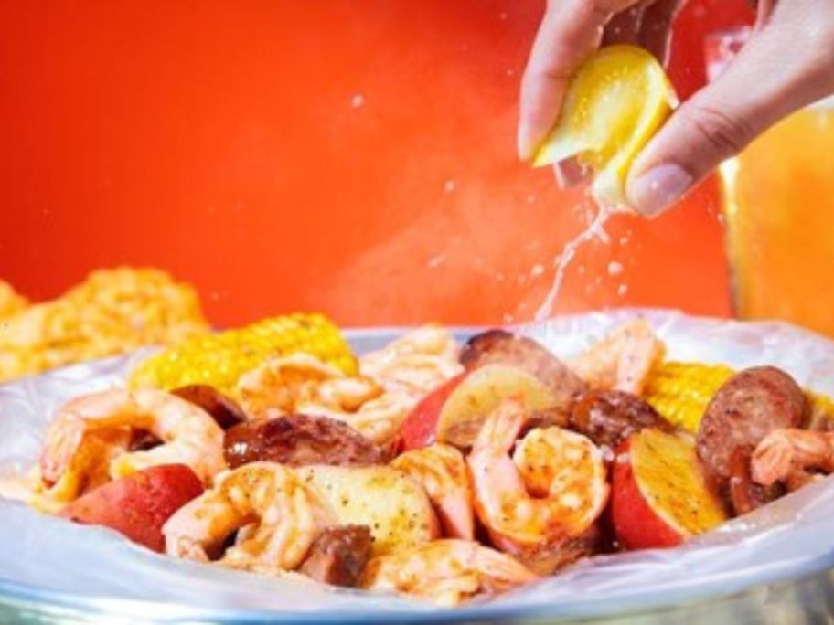 hand squeezing lemon on seafood boil