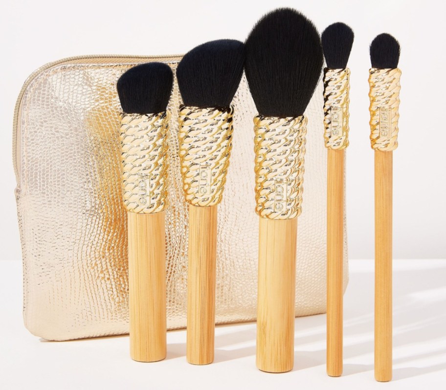 five gold makeup brushes and makeup bag