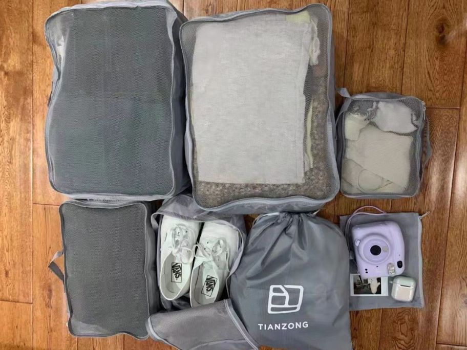 Packing cubes on the floor with clothing and shoes in them 