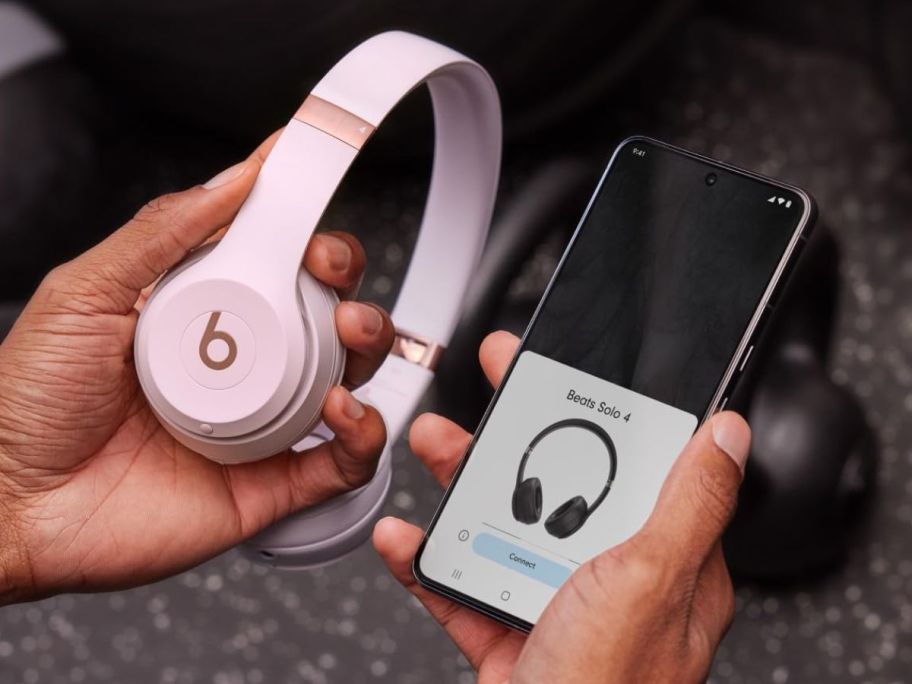 Hand holding Beats Solo 4 Wireless Bluetooth On-Ear Headphones next to a phone while pairing