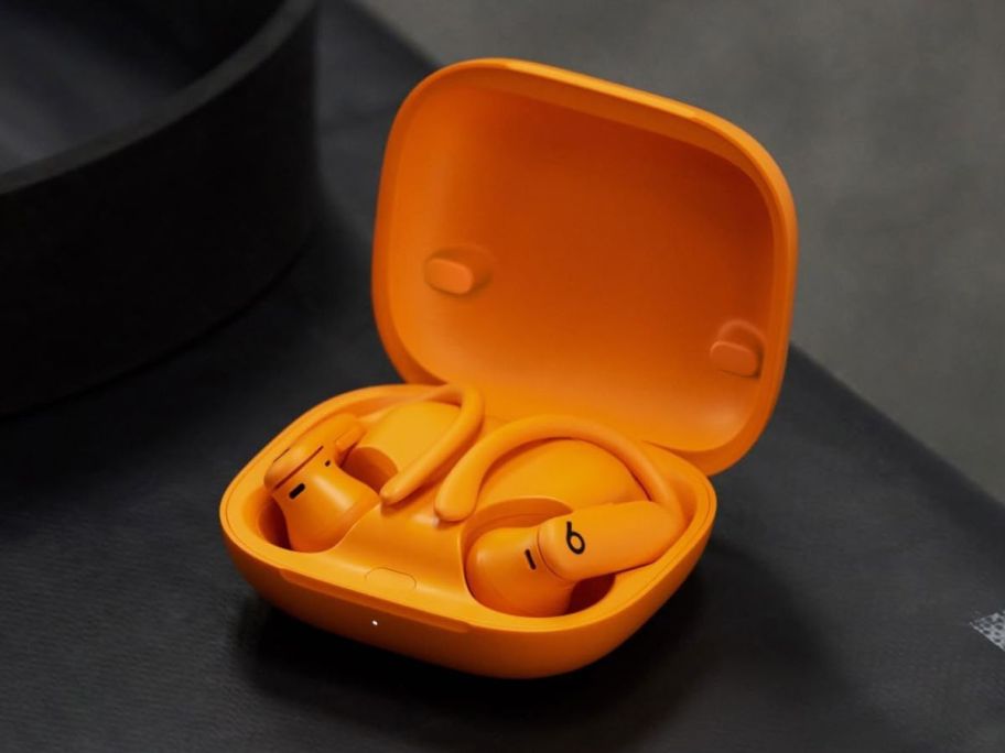 An orange pair of Beats Powerbeats Pro 2 Wireless Bluetooth Earbuds in the charging case
