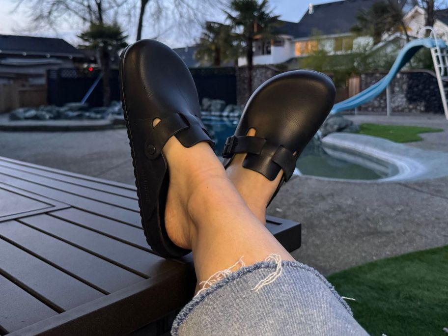 Feet crossed on a picnic table while wearing Birkenstock EVA Boston Clogs