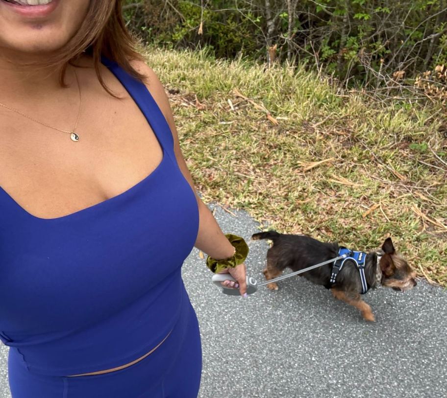 woman walking dog wearing cobalt blue sports clothing