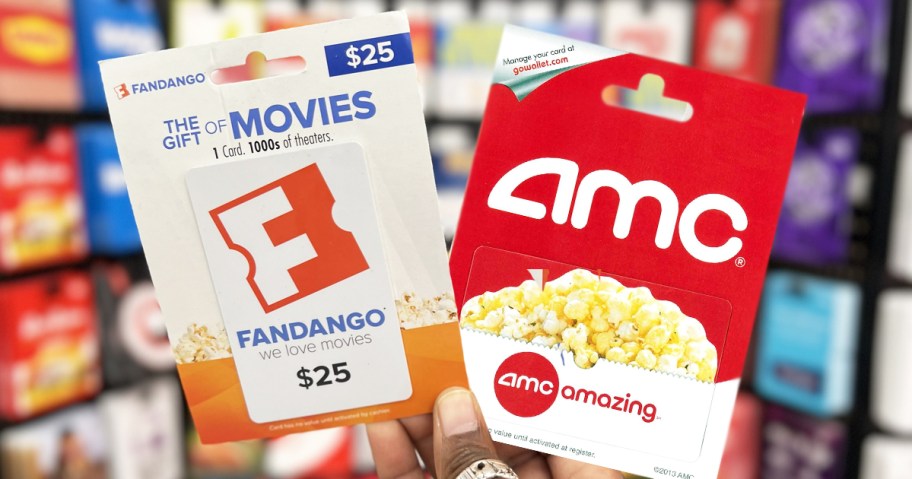 hand holding up Fandango and AMC gift cards in store