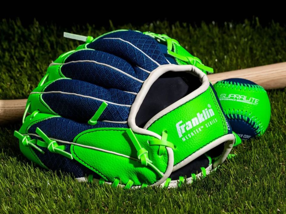 A green baseball glove, ball, and a bat on a field