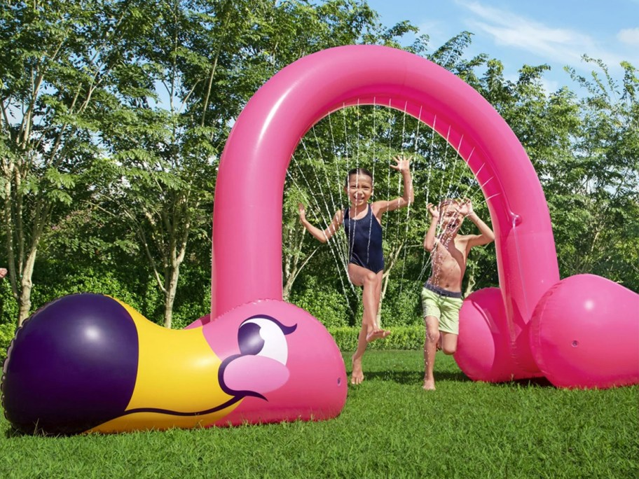 pink flamingo sprinkler with kids playing under it 