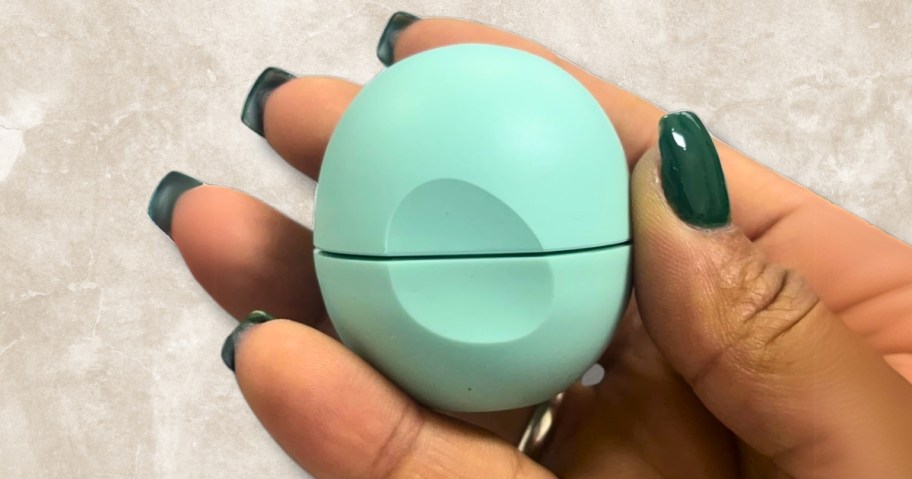 hand holding a green round lip balm container