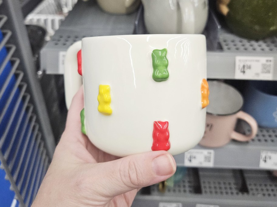 hand holding a white coffee mug with colorful gummy bears