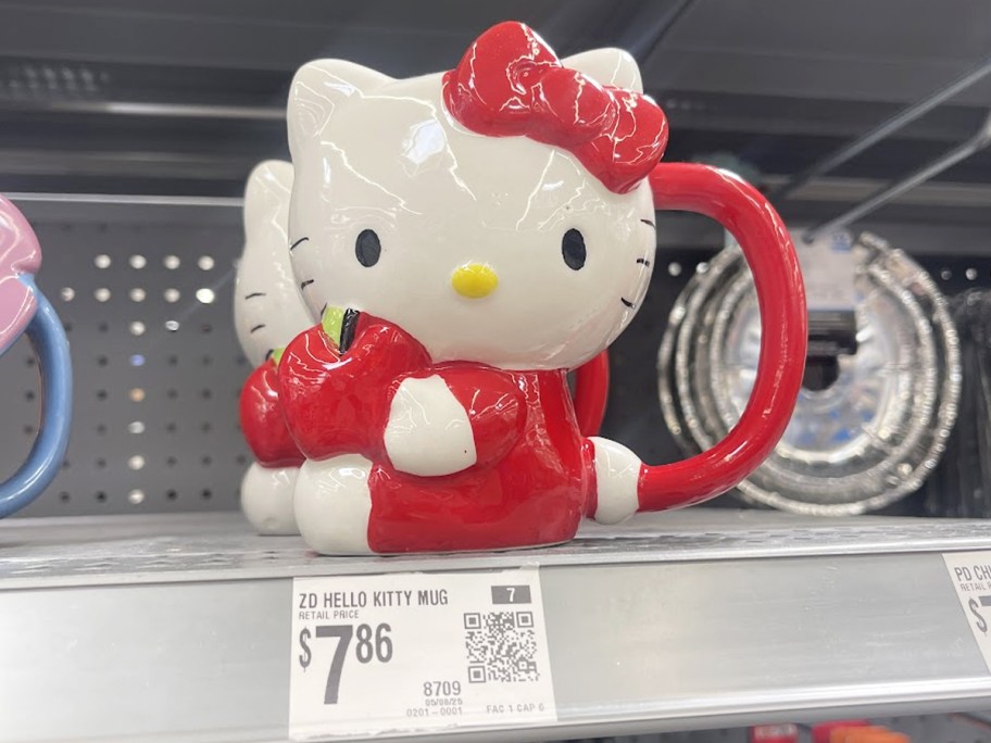 hello kitty holding an apple shaped mug on store shelf