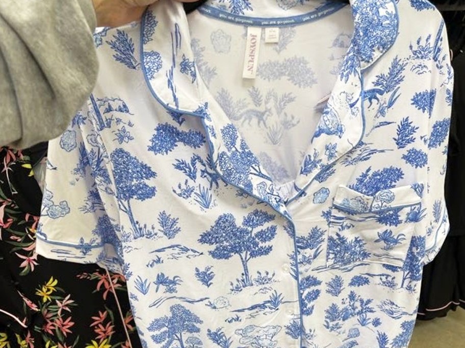hand holding up a white and blue printed pajama set in store