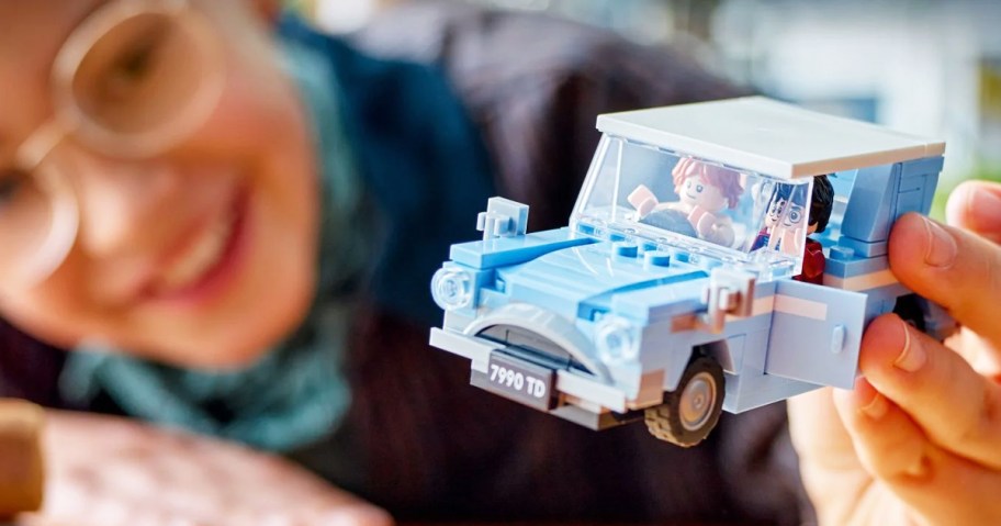 girl holding up blue LEGO Harry Potter Flying Ford Anglia set
