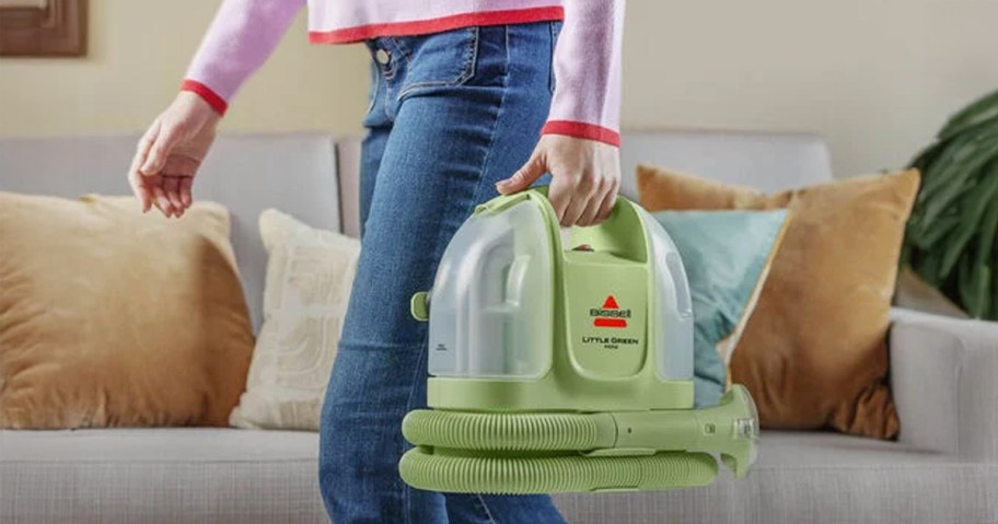 Little Green Mini Cleaner being carried in a living room by a woman