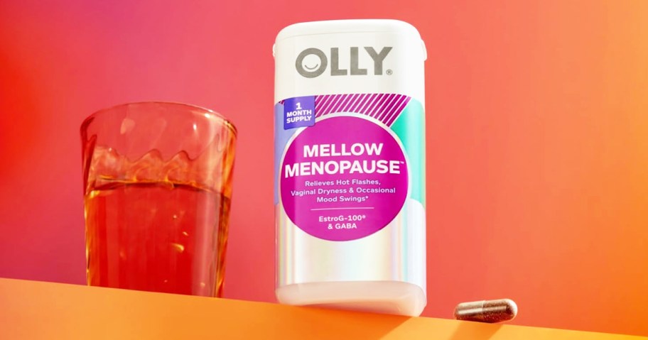 bottle of OLLY Mellow Menopause supplement next to a glass of water