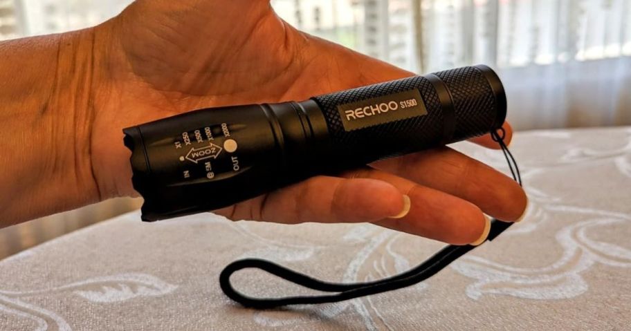 A person holding a black flashlight