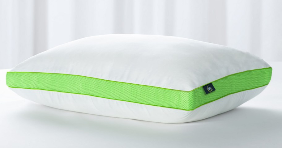 a green and white serta bed pillow displayed on a bed