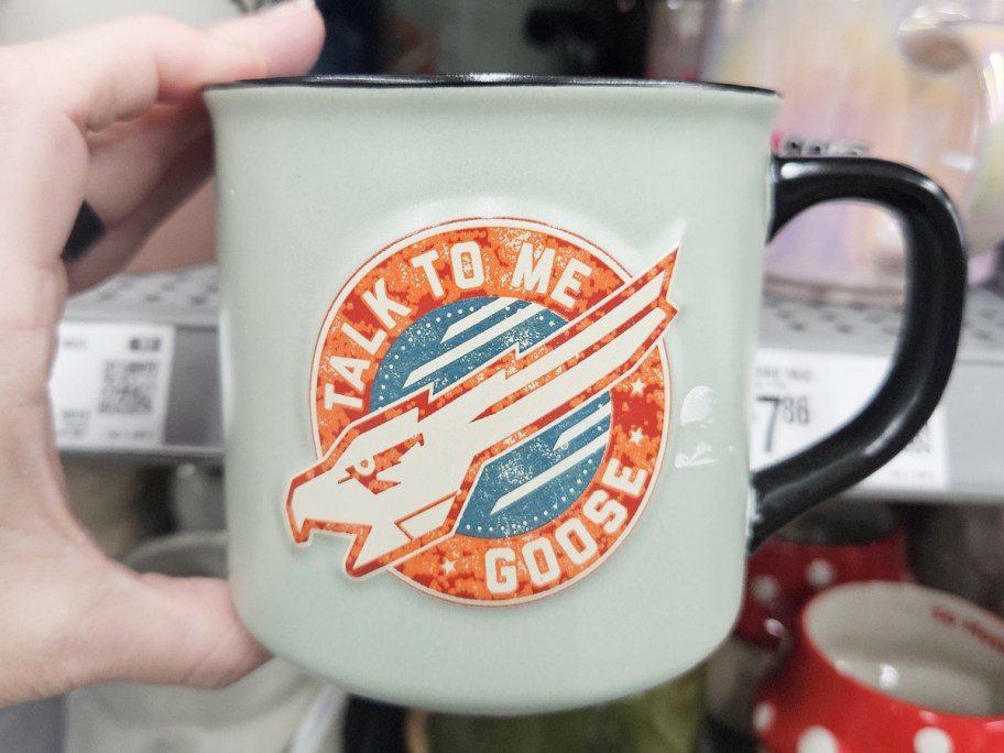 hand holding a coffee mug that says talk to me goose