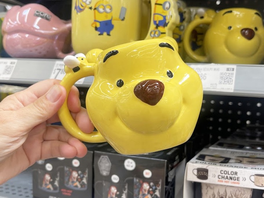 hand holding up yellow Winnie the Pooh Shaped Mug