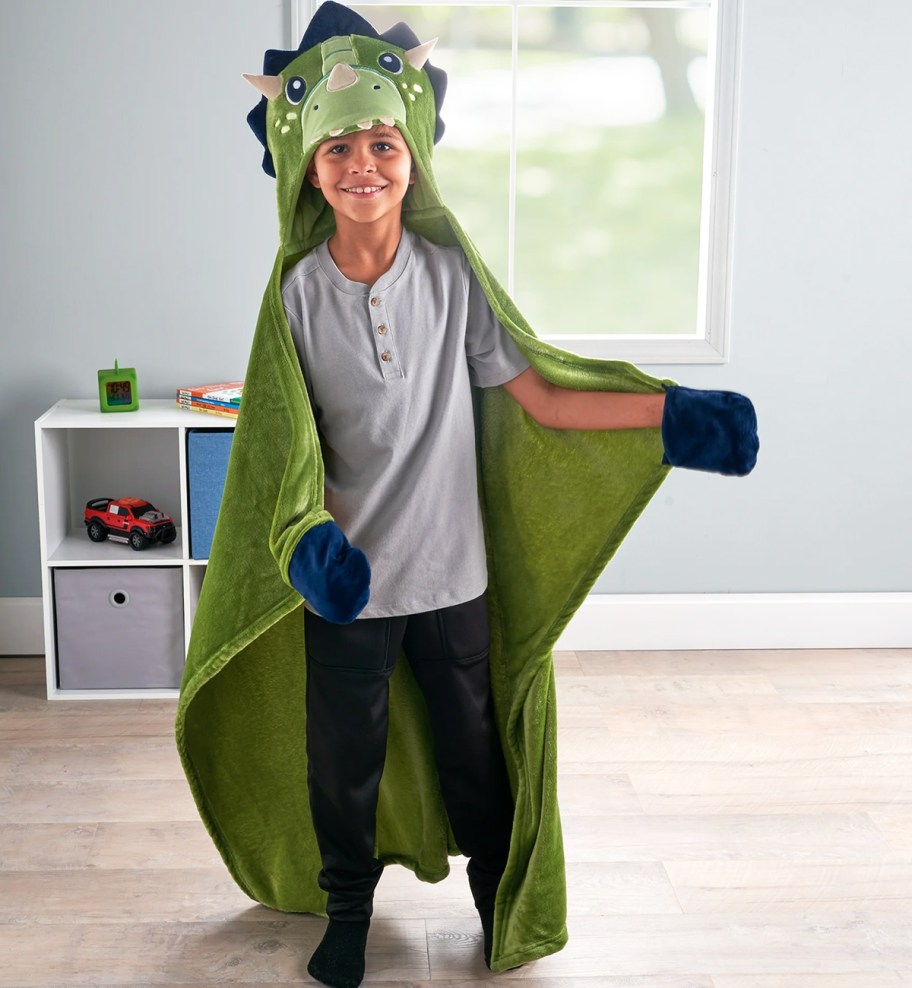 boy wearing a dinosaur hooded throw blanket