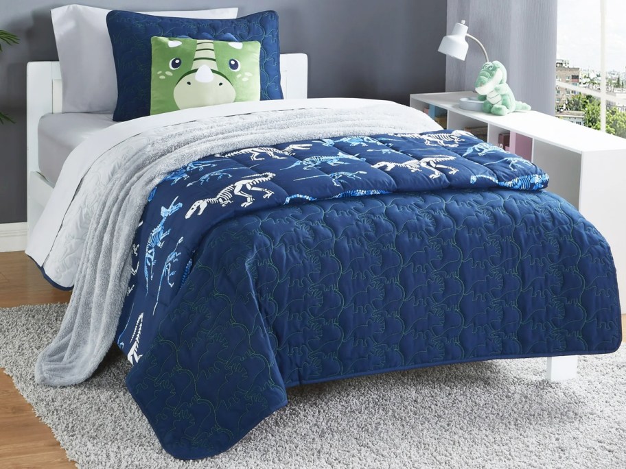 blue dinosaur quilt set on bed