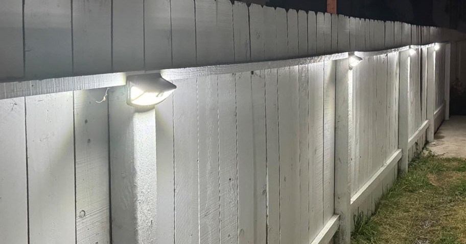 solar lights hanging on a white wooden fence
