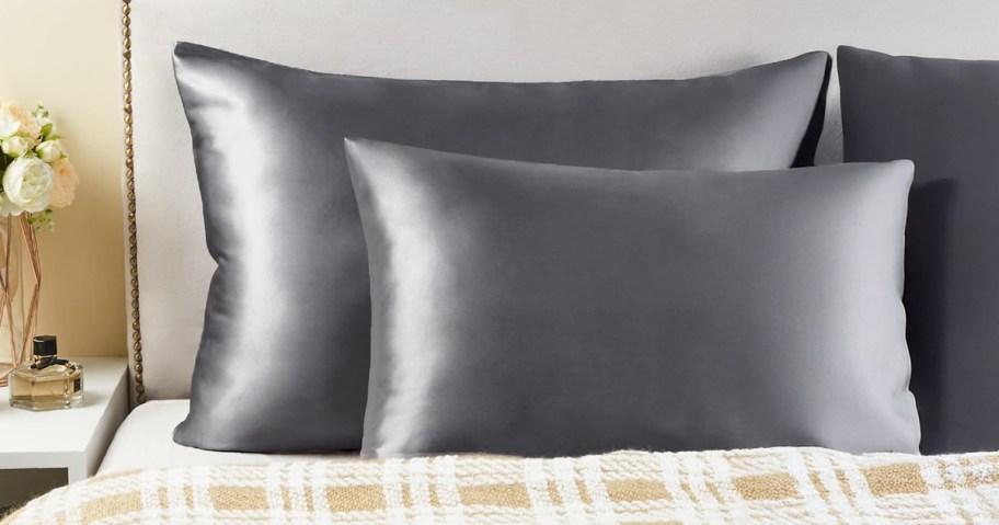 two grey pillowcases on pillows placed on top of a bed