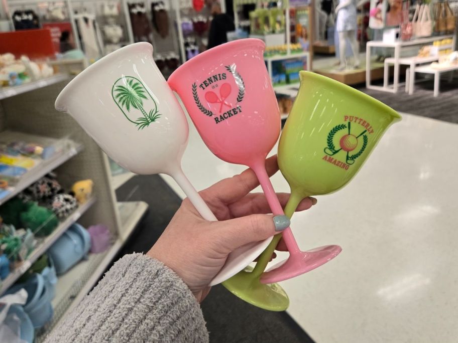 a white, pink, and lime green Stemmed Drinkware pieces in hand in store