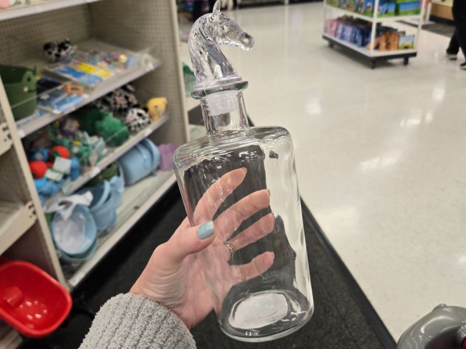 glass decanter with horse head on top in hand in store