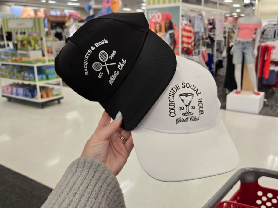 a black and a white Athletic & Girls Club Trucker Hat in hand in store