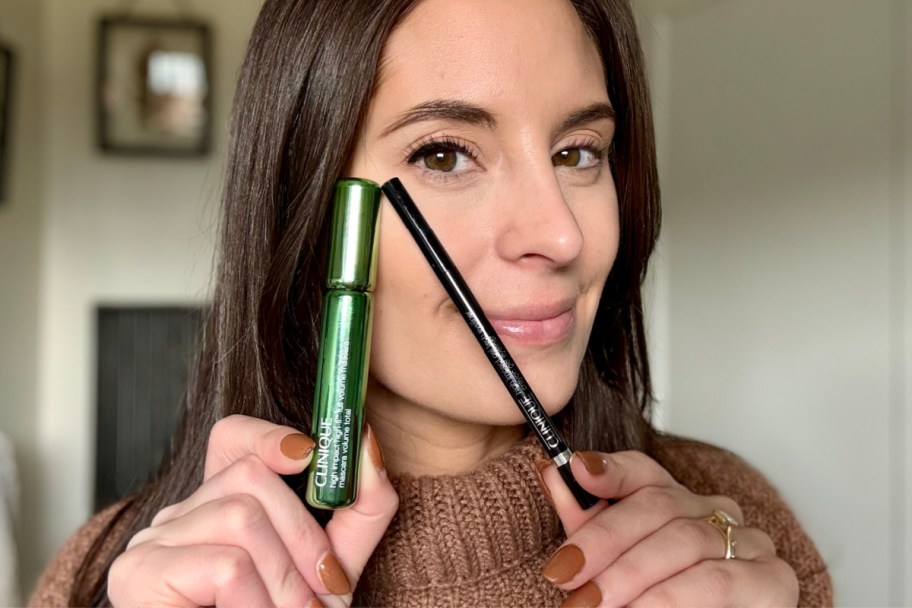 woman holding mascara and eyeliner up to eye