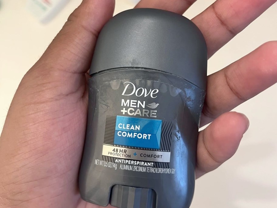 holding a travel size stick of deodorant