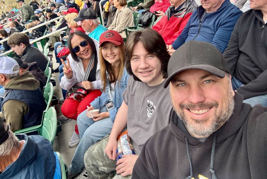 family sitting in row of seats at baseball game