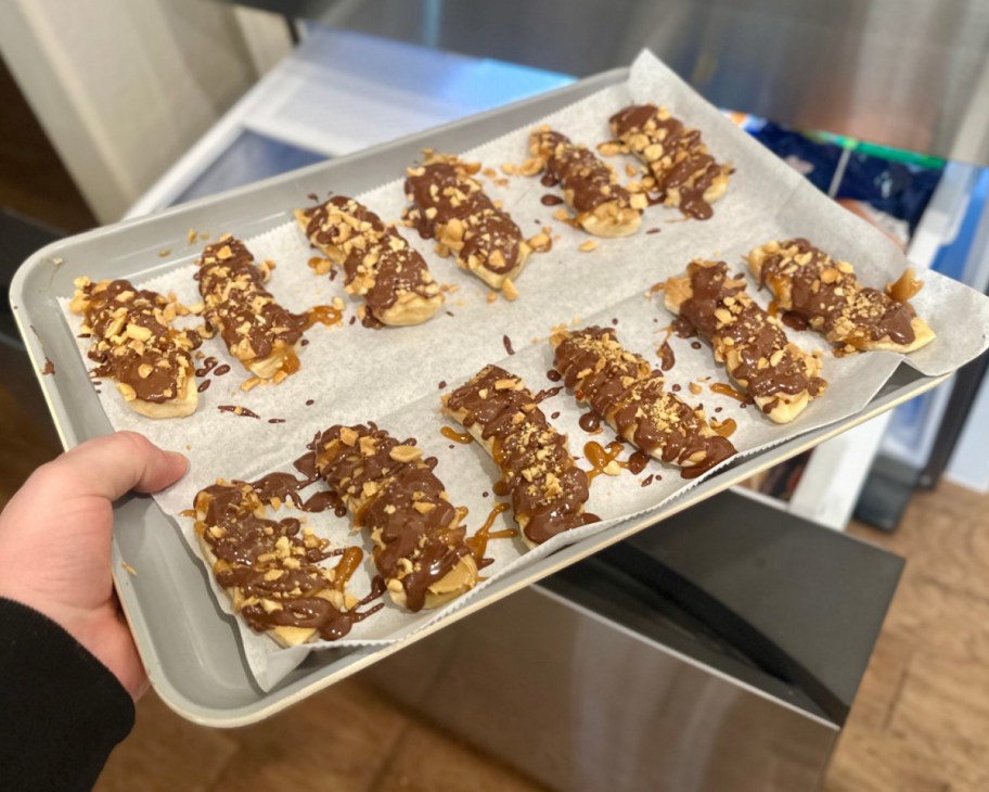 hand holding tray of frozen bananas going into freezer