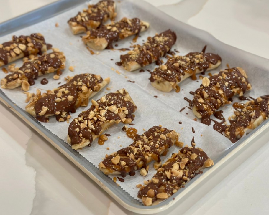 chocolate and peanut covered bananas on cookie sheet 