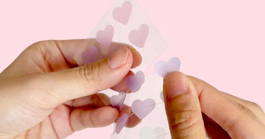 hand holding heart shaped pimple patches