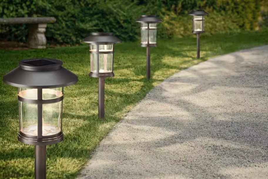 4 black led solar lights in grass near sidewalk