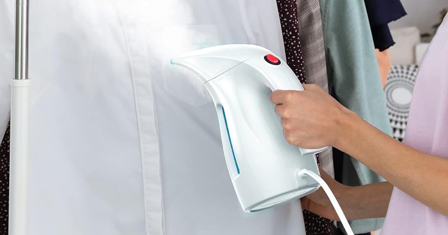 person using clothing steamer to remove wrinkles from a shirt