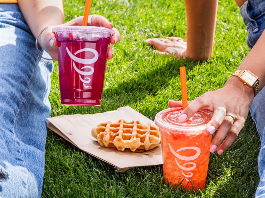 women sitting in grass holding jamba juice cups