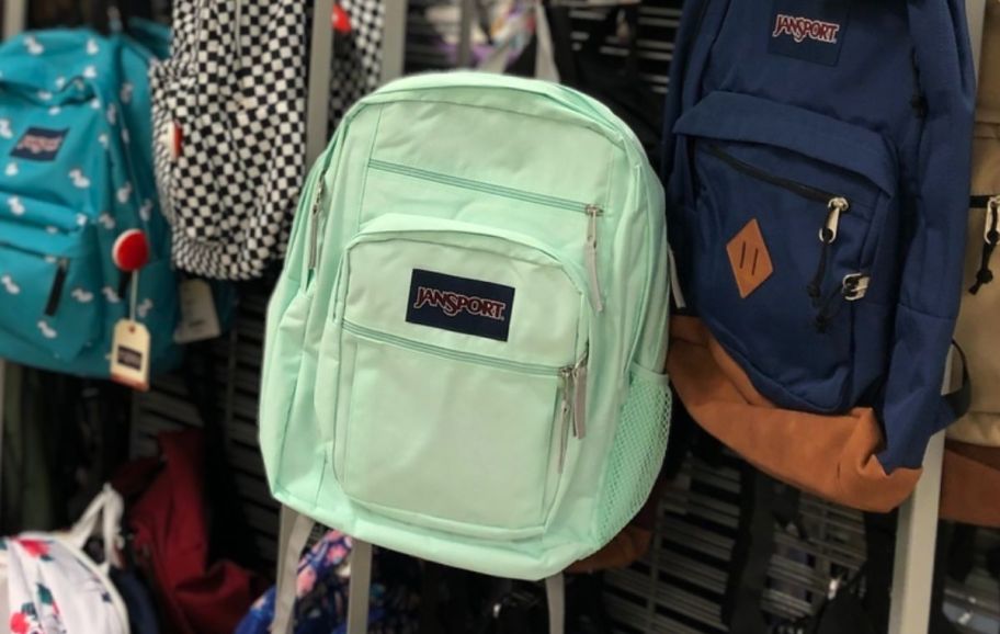 light green jansport backpack on a rack in a store