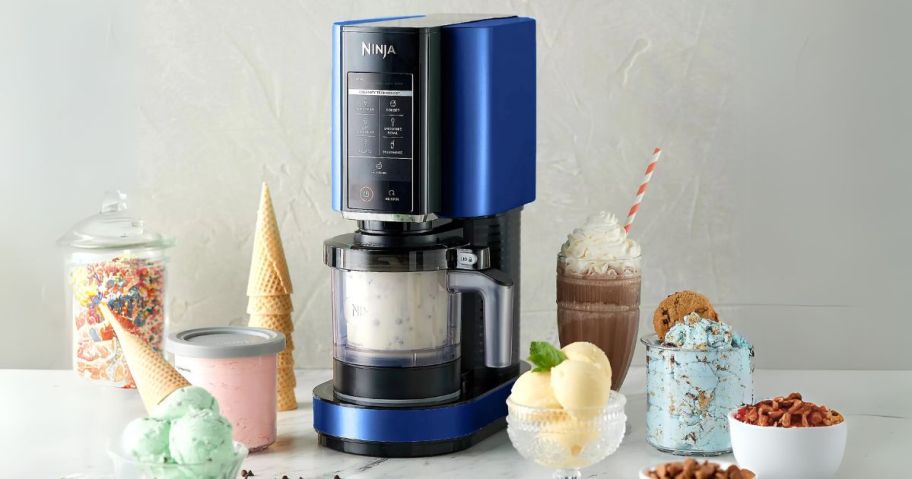 blue ninja creami on counter with ice cream, shakes, cones, and toppings all around it