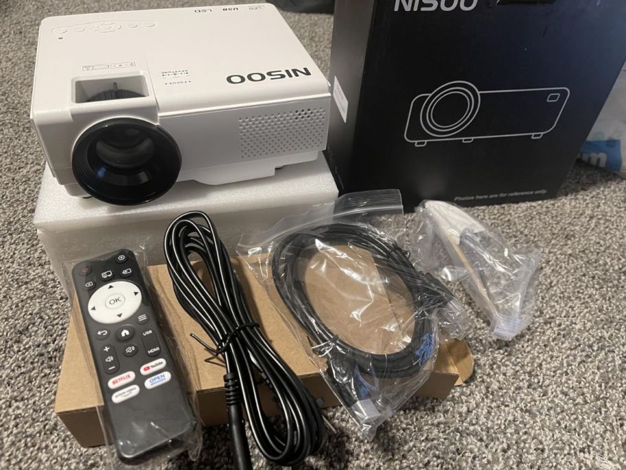 mini movie projector shown with package contents including cables and remote