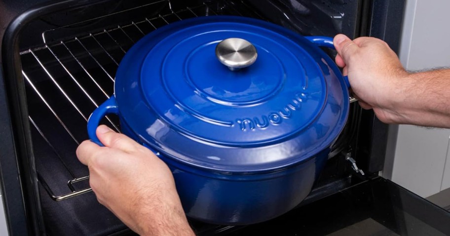 person putting dark blue dutch oven in the oven